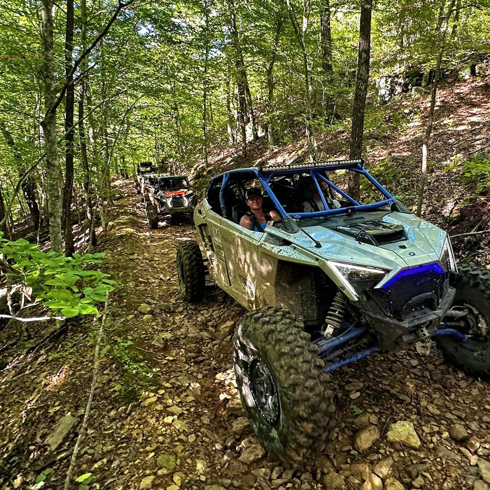 SxS machines riding on a wooded off road trail